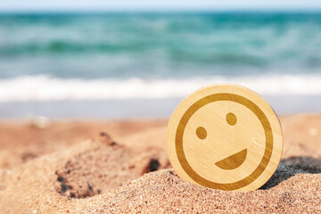 Obraz premium Wooden circle with smiley face icon on a sandy beach. Concept of customer satisfaction, happiness, and positive travel experience.