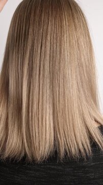Blonde hair being combed with a wooden comb in slow motion. Texture of female hair close-up.
