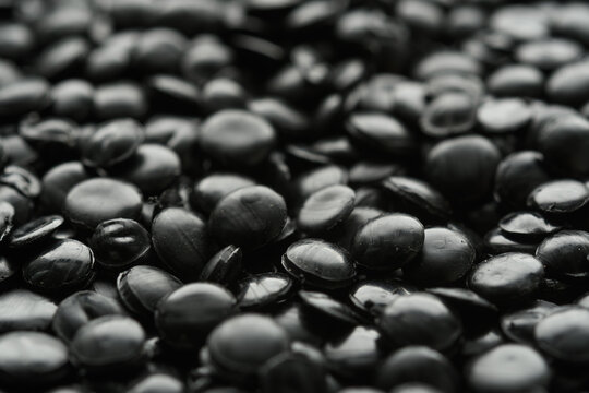 Glossy black polyethylene pellets fill macro frame with moody industrial texture for plastics production and recycling use.