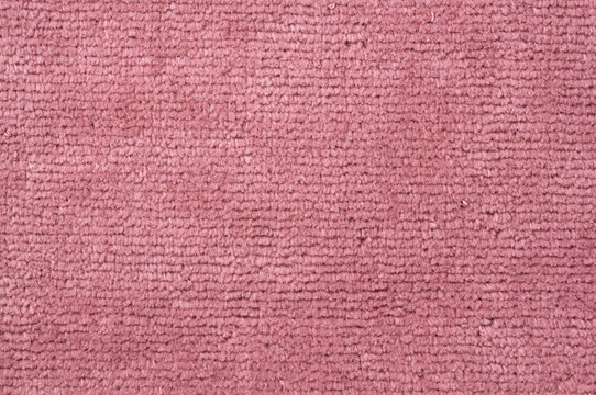 Close-up texture of a soft pink carpet with a ribbed pattern