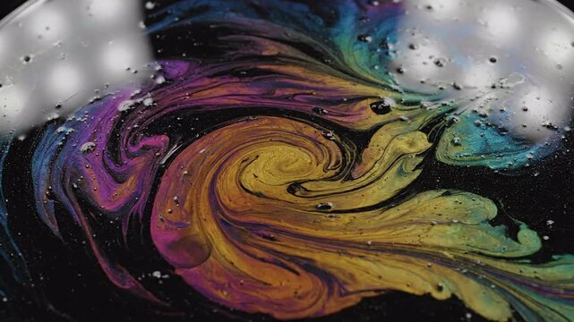 Abstract swirling rainbow oil and water on black background, iridescent colors and fluid dynamics, small bubbles forming intricate patterns, perfect for science or design backdrops