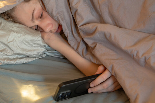 Teen Boy Using Smartphone in Bed Late at Night, for Sleep Problems, Digital Addiction, Doom scrolling, Teen Mental Health, Burnout, Bedtime Screen Habits, and Modern Parenting Topics