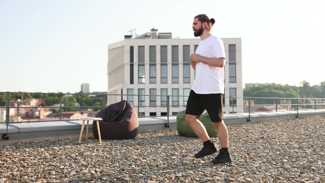 A man performs lunges on a rooftop, enjoying the urban view and focusing on fitness