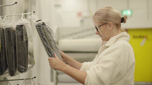 Woman choosing carpet and rug samples in home improvement store while searching for interior decoration ideas