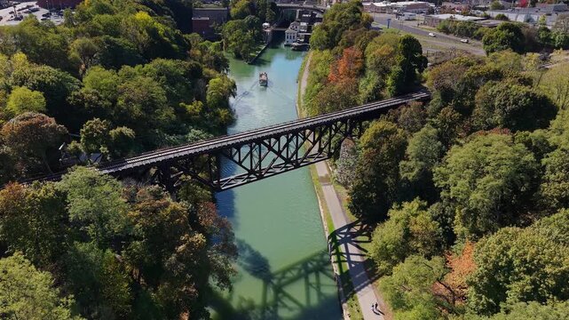 Aerial view of historic railway bridge over Erie Canal in Lockport, New York, USA with boat approaching locks and autumn forest