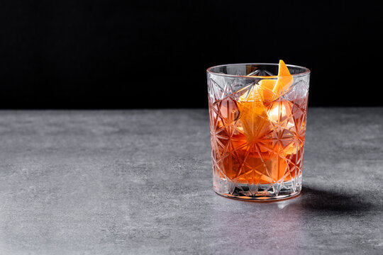 Old Fashioned Cocktail with Orange Peel on gray stone and black background. Copy space