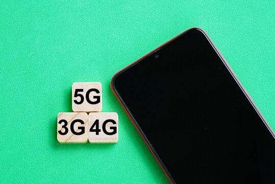 Hand phone and wooden blocks printed 3G 4G 5G. Telecommunications concept. Wireless connection technology. Internet speed. Mobile network performance
