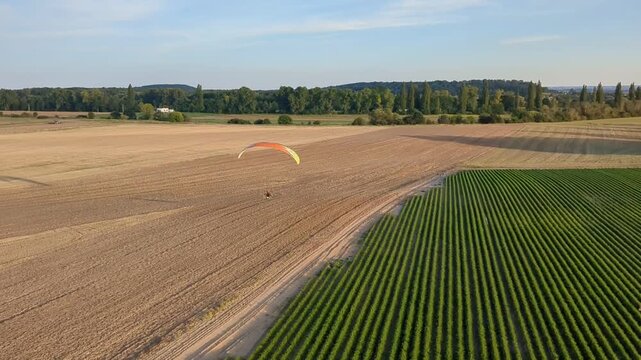 Motorized paragliding pilot flying low above ground enjoying powered flight adventure