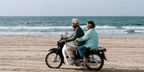 Fototapeta premium Older couple riding motorcycle along flat sandy beach shoreline