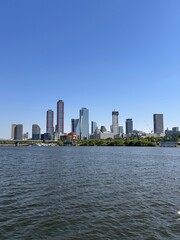 Obraz premium City skyline stands tall near the river under clear blue sky with tall buildings and urban landscape seen in daylight