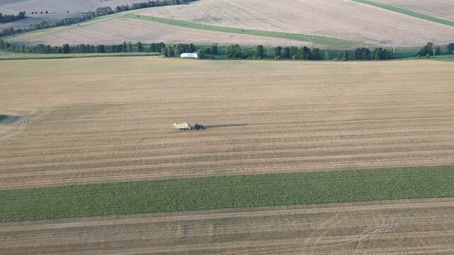 Tractor with forage wagon collecting hay rows on field aerial panorama farming scene