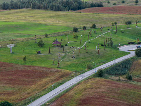 Aerial view of the Hill of Angels featuring numerous wooden sculptures scattered across green meadows and rolling hills in Traku rajonas, Vilniaus apskritis, Lithuania.