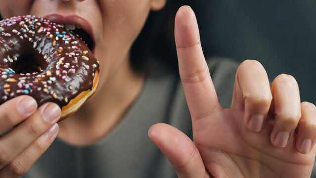Finger stopping sugary snack before bite, self-control moment, macro tension