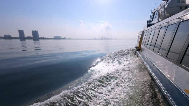 Real-time 60fps side view of a ferry crossing the calm waters of the Singapore Strait, with a distant city skyline visible.