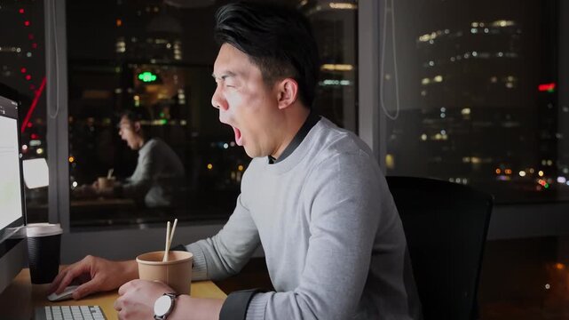 Tired businessman office worker feeling sleepy and stressed at desk eating instant noodles while working late night overtime amidst high-pressure deadline in front of computer, city lights background