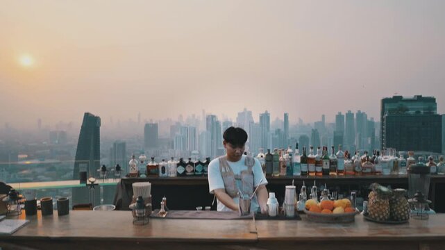 Cinematic footage of a rooftopbar in Bangkok during sunset. Barkeeper mixing drinks.