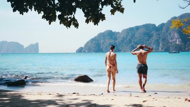 Young couple entering the ocean in Koh Phi Phi, Thailand. Beautiful scenery. Romantic ambience.