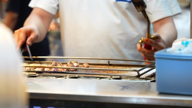 Street food vendor grilling meat with a flame torch at an asian night market stall in Taiwan