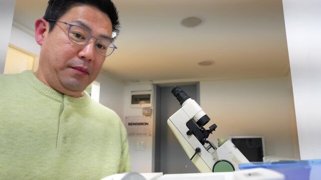 Professional asian ophthalmologist manufacturing and checking lenses for eyeglasses in his optical shop