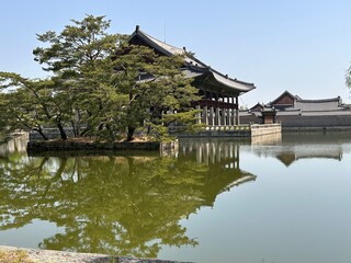 Naklejka premium View of a traditional building by a pond with trees and reflections in the water during a clear day in a historical site