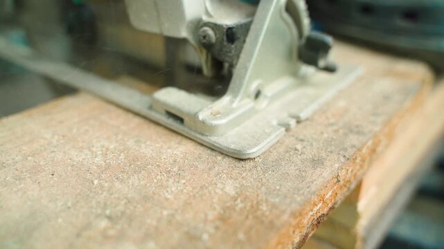 Close up of circular saw cutting wooden board with sawdust flying. Power tool in action during woodworking and carpentry work