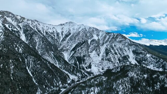 Frisco Gulch mountain range with snow covered peaks and dense evergreen forest, aerial drone overview