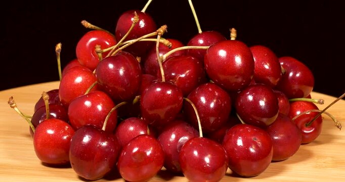 Close-up footage of napoleon cherries on a wooden tray against a black background.