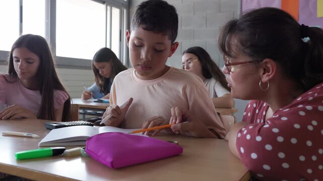 Teacher helping a young student with his homework in the classroom