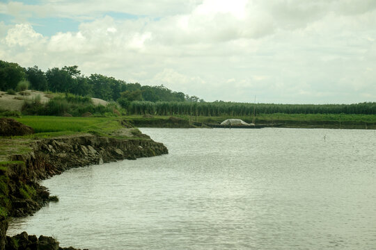 Clay riverbank borders a calm river. Wooden fishing boats