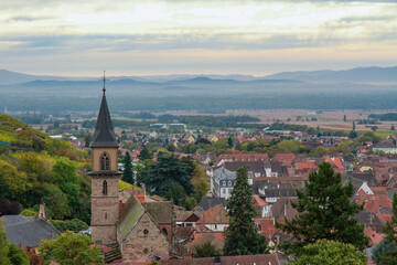 Fototapeta premium Panoramic aerial view of Ribeauville town with Saint Gregoire church tower. Scenic autumn landscape of Alsace wine region with red roofs and Vosges mountains, France.