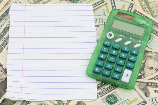 Blank lined paper with twenty dollar bill cash with calculator