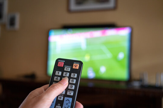 Watching football match at home, close up on remote control.