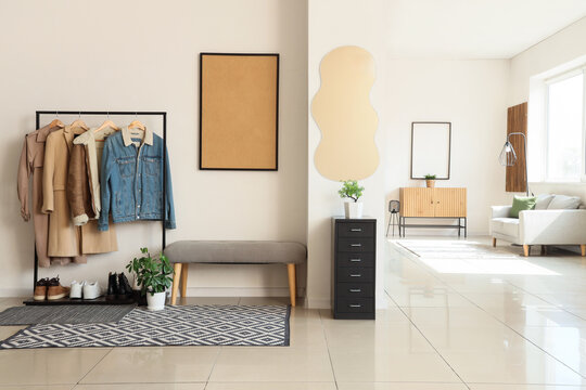 Interior of light room with mirror, soft bench and coat rack