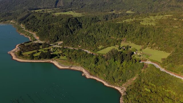 Cinematic Perspective of Drone Flying Over Water Toward Forest Mountain Road