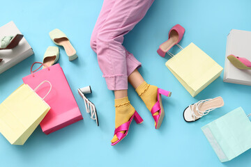 Naklejka premium Legs of young woman with different stylish high heel sandals and shopping bags on blue background