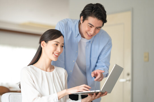 リビングでパソコンを見る笑顔の夫婦	