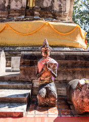 Naklejka premium Weathered female guardian figure stands within a sacred temple site surrounded by historic stone structures and cultural heritage architecture.