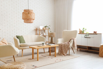 Interior of light living room with sofa, armchairs and window