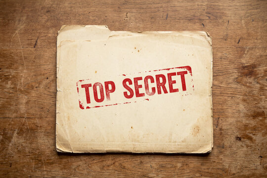 old file folder with top secret stamp containing classified confidential information document on desk