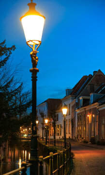 Dutch canal house with street lighting on, Onze Lieve Vrouwetoren clock tower in the background, Amersfoort, Netherlands, European lifestyle