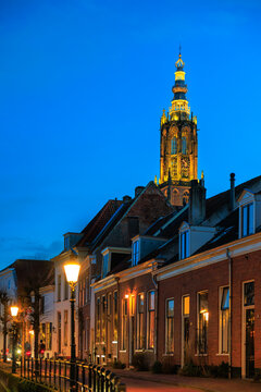 Dutch canal house with street lighting on, Onze Lieve Vrouwetoren clock tower in the background, empty space, Amersfoort, Netherlands, European lifestyle