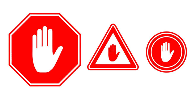 A close-up view of three stop signs with hands on them.