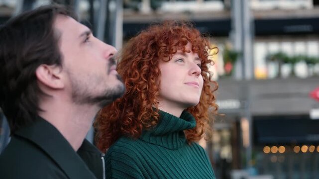 Hopeful young couple standing outdoors with contemplative and faithful expressions