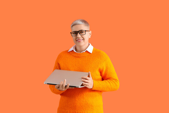Female programmer with laptop on orange background