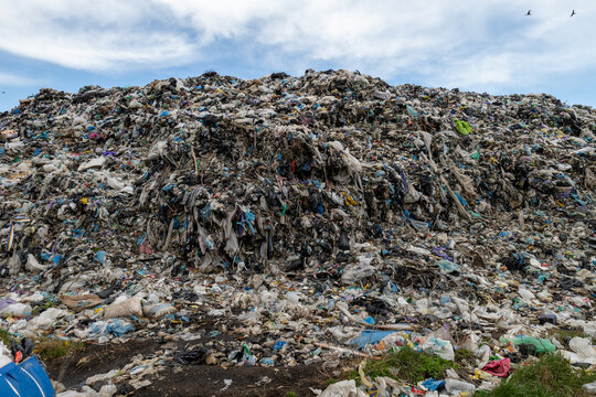 Garbage dump contains a large amount of mixed waste material with plastic and debris scattered across the area in daylight