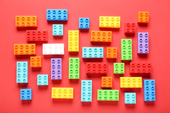 Colorful plastic building blocks on red background