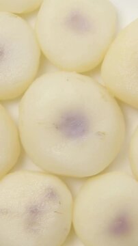 Slowly rotating boiled and peeled water chestnuts arranged on a white plate, Close-up view