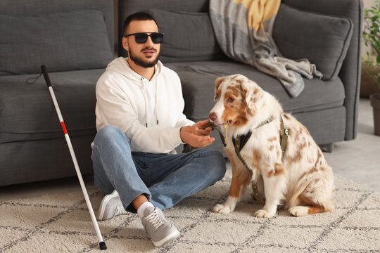 Blind young man taking key from guide dog at home