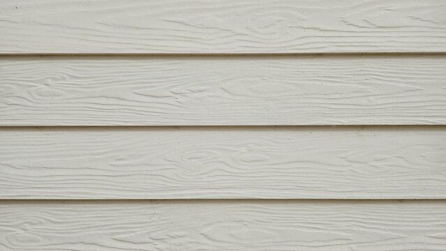 Cream lap siding wall texture. Cream-colored lap siding wall texture with natural wood grain. Horizontal synthetic wood grain siding.