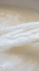 Obraz premium Close Up of Creamy Milk Surface with Gentle Foam Waves in Soft Lighting